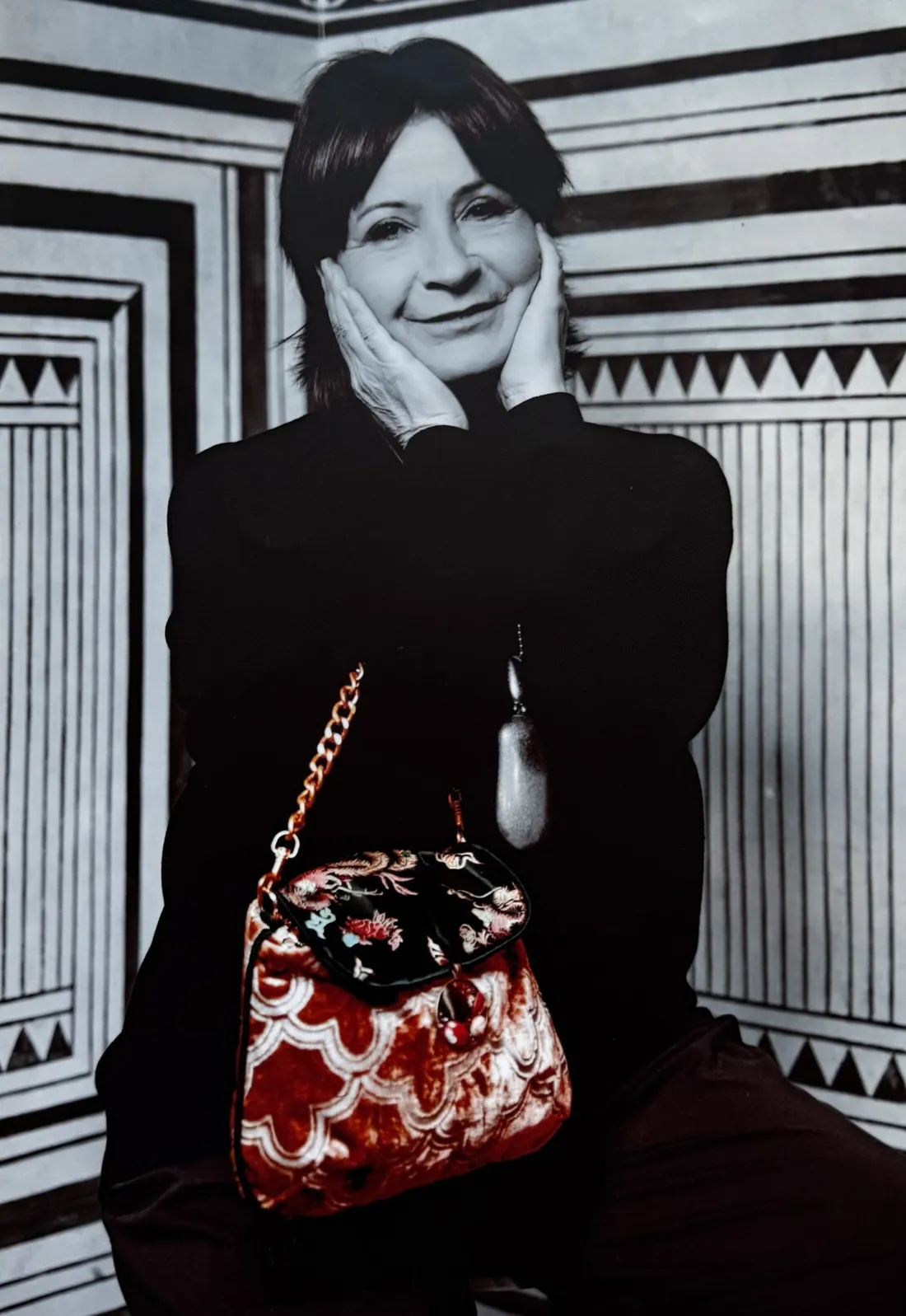 Ritratto in bianco e nero con una borsa Moki in velluto rosso, l'unico elemento a colori